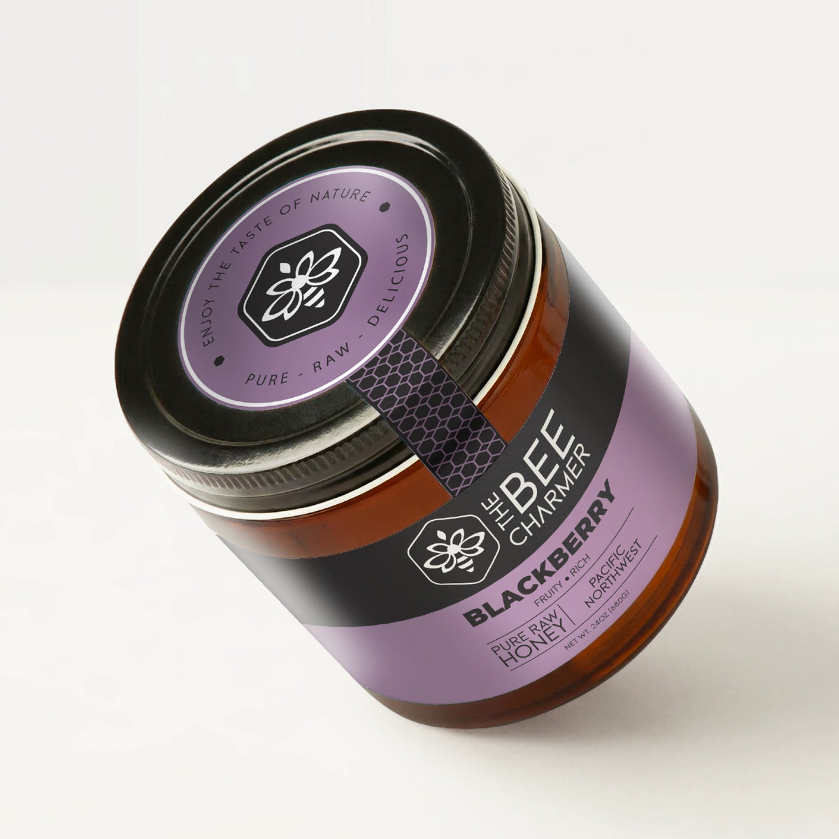 Pure raw Blackberry honey in a signature Bee Charmer branded 24oz wide-mouth glass jar showing the top of the jar label.