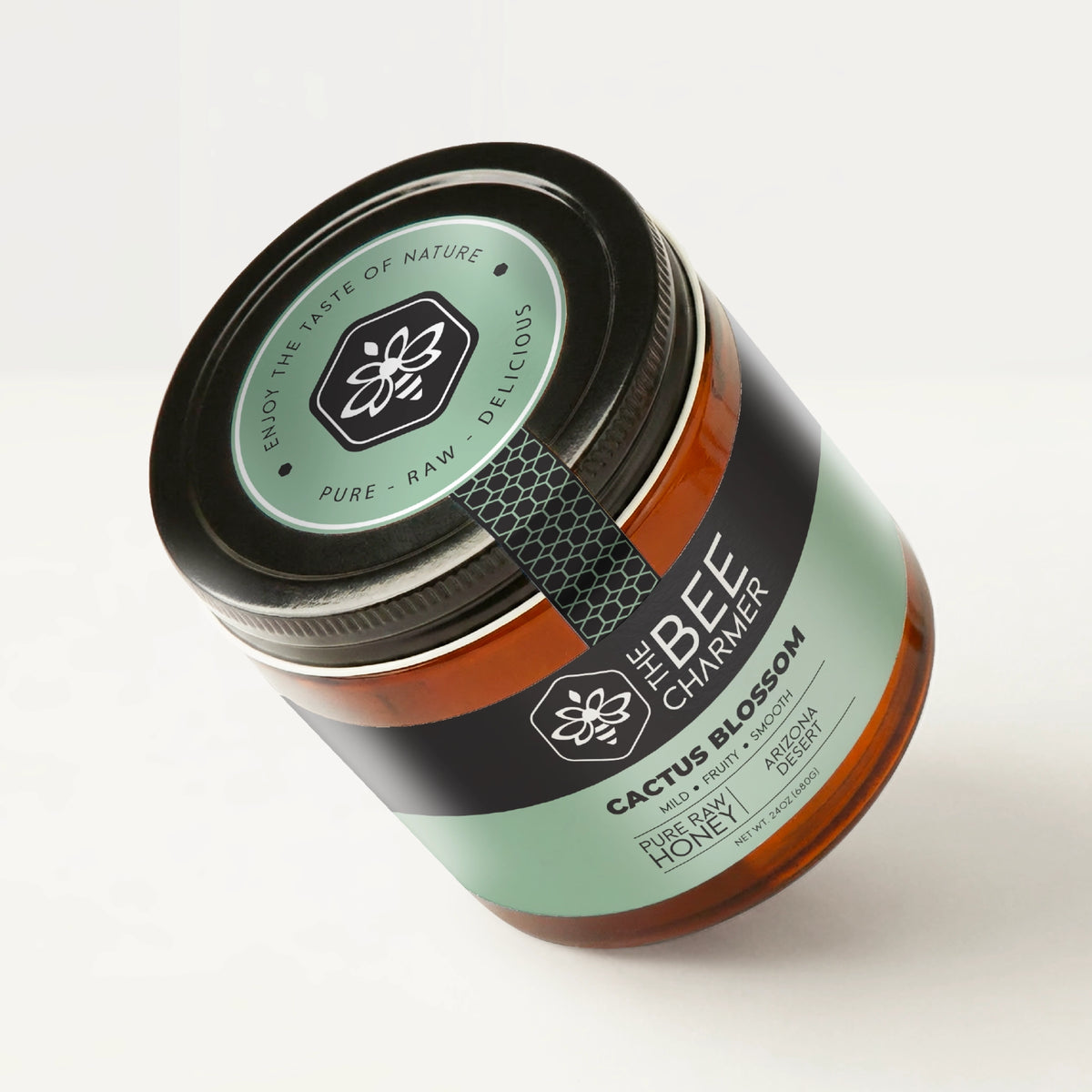 Pure raw Cactus Blossom Honey in a signature Bee Charmer branded 24oz wide-mouth glass jar showing the top of the jar label.