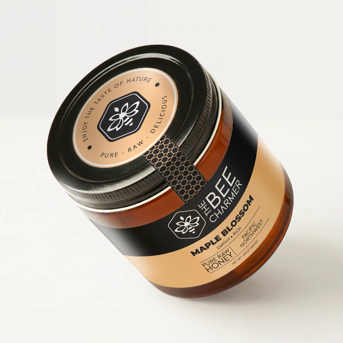 Pure raw Maple Blossom Honey in a signature Bee Charmer branded 24oz wide-mouth glass jar showing the top of the jar label.