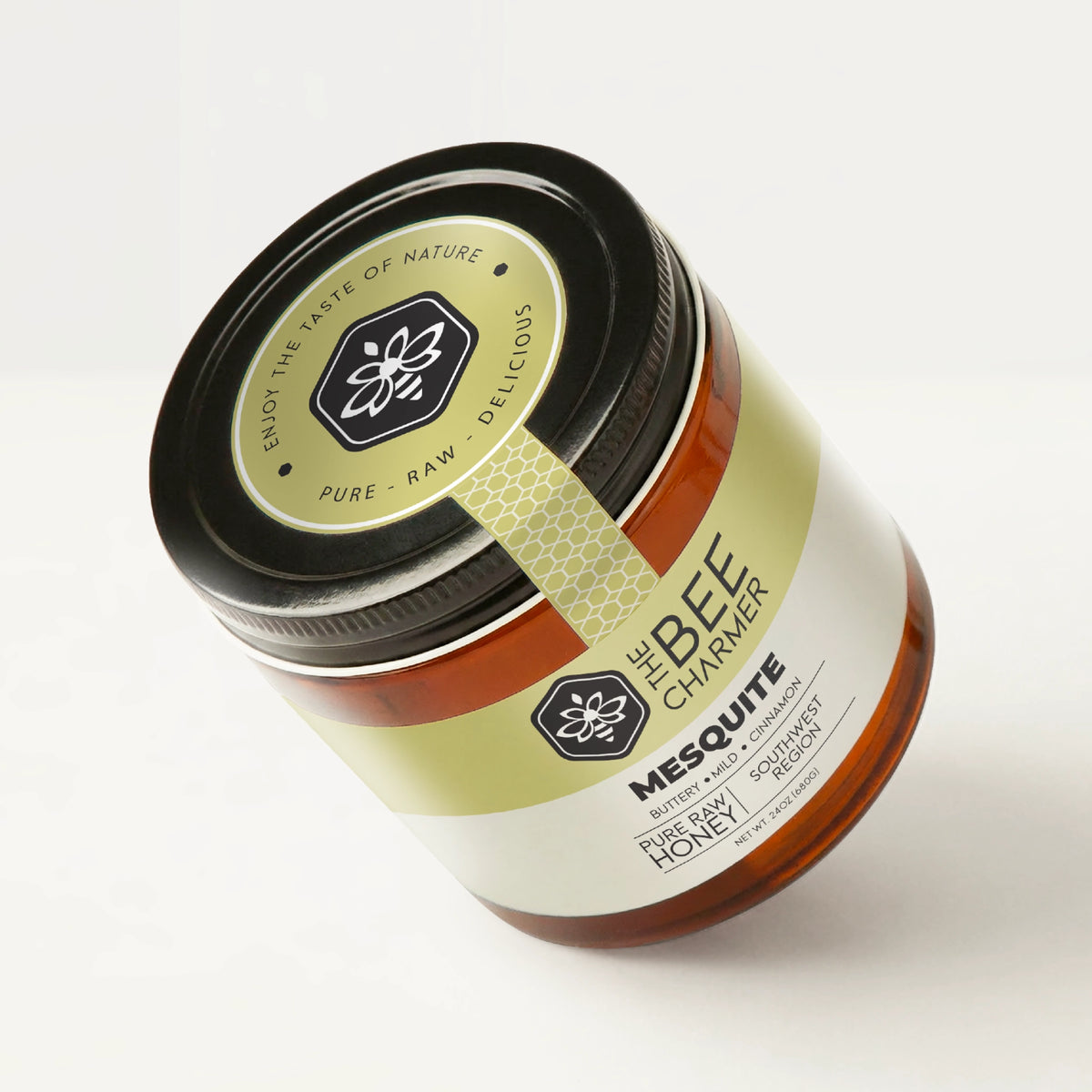 Pure raw Desert Mesquite Honey in a signature Bee Charmer branded 24oz wide-mouth glass jar showing the top of the jar label.
