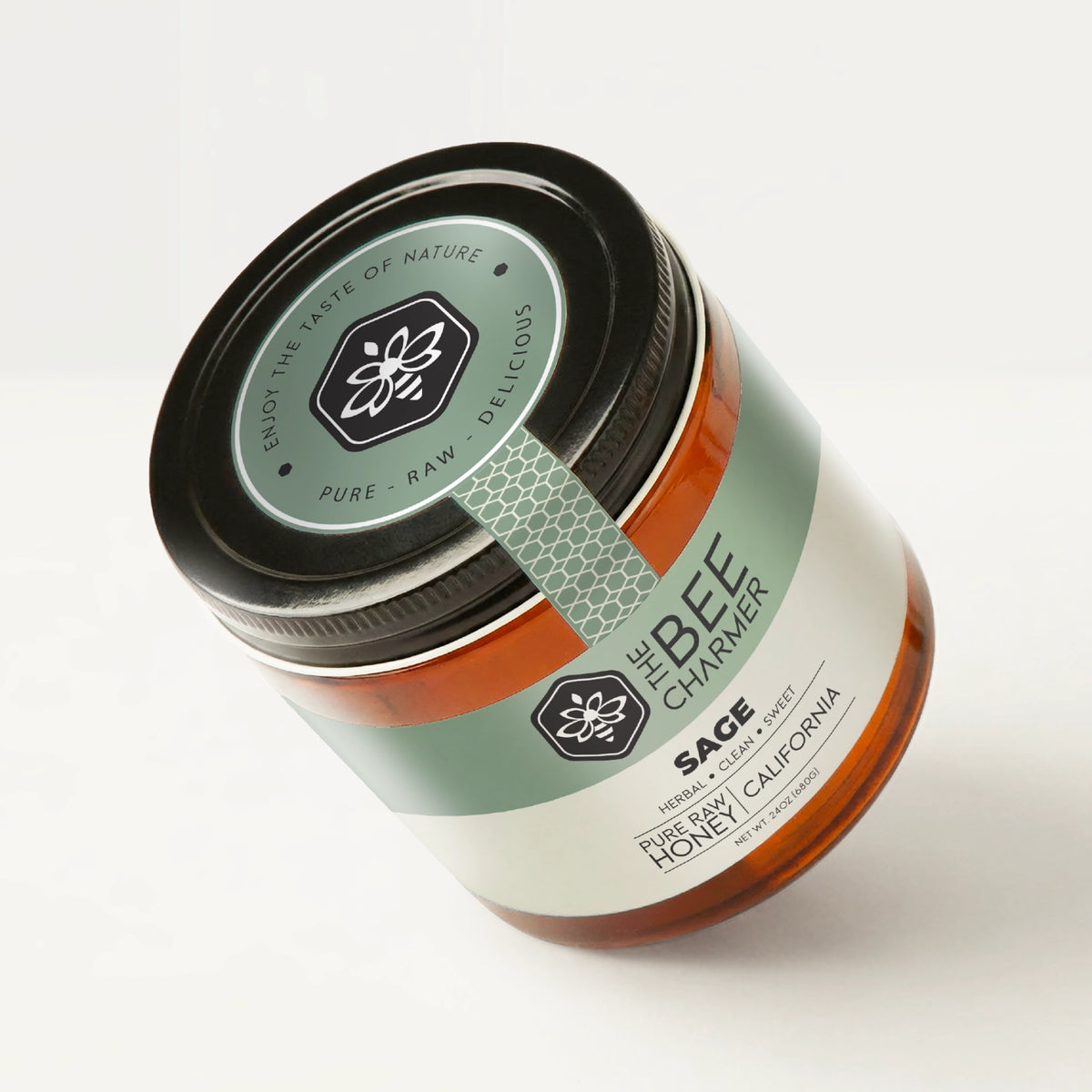 Pure raw Sage Honey in a signature Bee Charmer branded 24oz wide-mouth glass jar showing the top of the jar label.