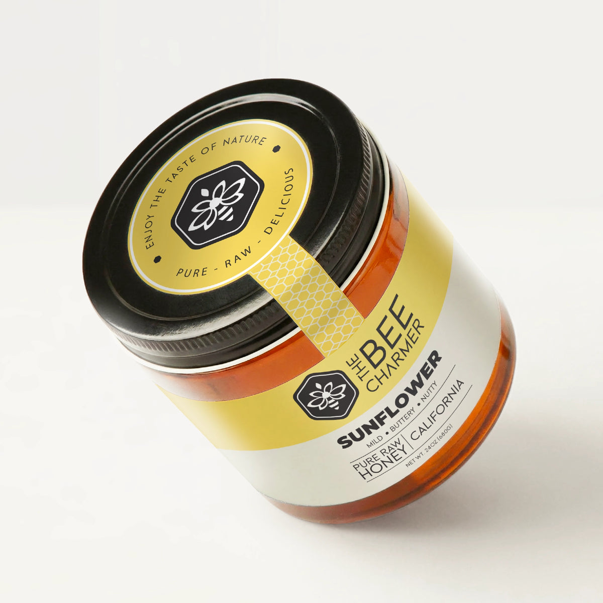 Pure raw Sunflower Honey in a signature Bee Charmer branded 24oz wide-mouth glass jar showing the top of the jar label.