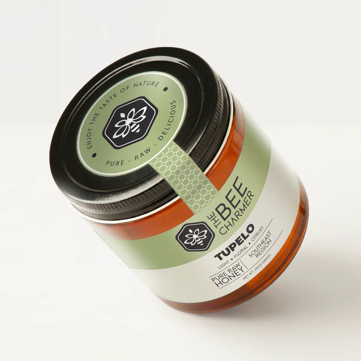 Pure raw Tupelo Honey in a signature Bee Charmer branded 24oz wide-mouth glass jar showing the top of the jar label.
