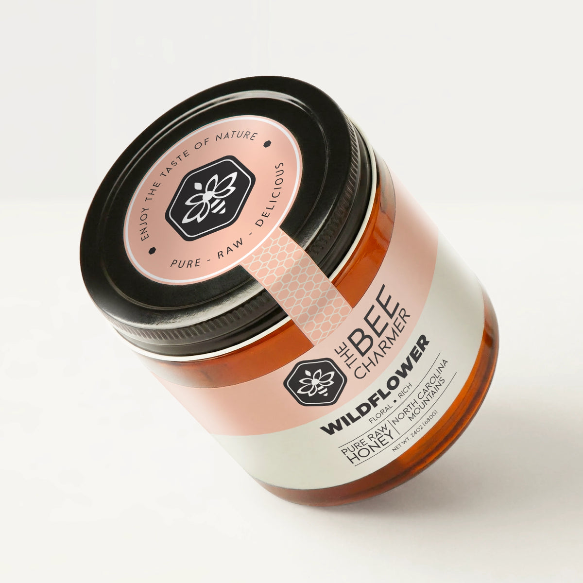 Pure raw Wildflower Honey in a signature Bee Charmer branded 24oz wide-mouth glass jar showing the top of the jar label.