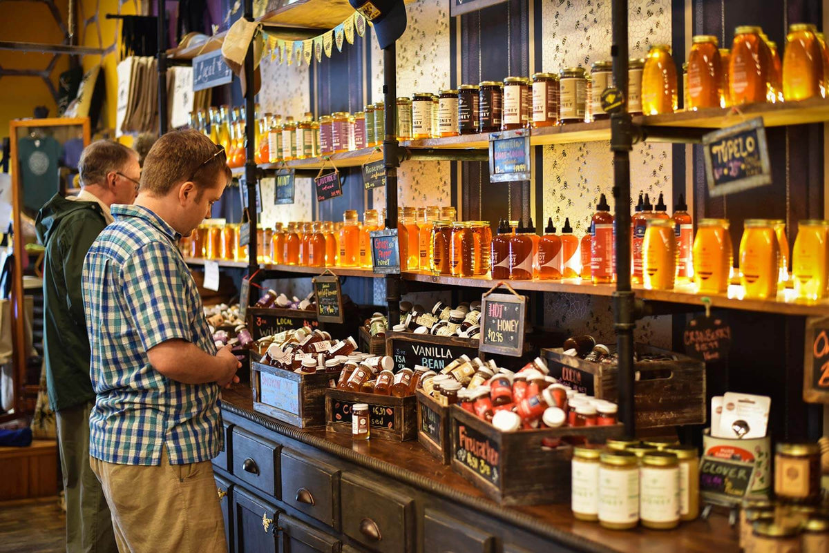 An inside view of The Bee Charmer's Asheville, NC retail location showing shelves full of honey jars.