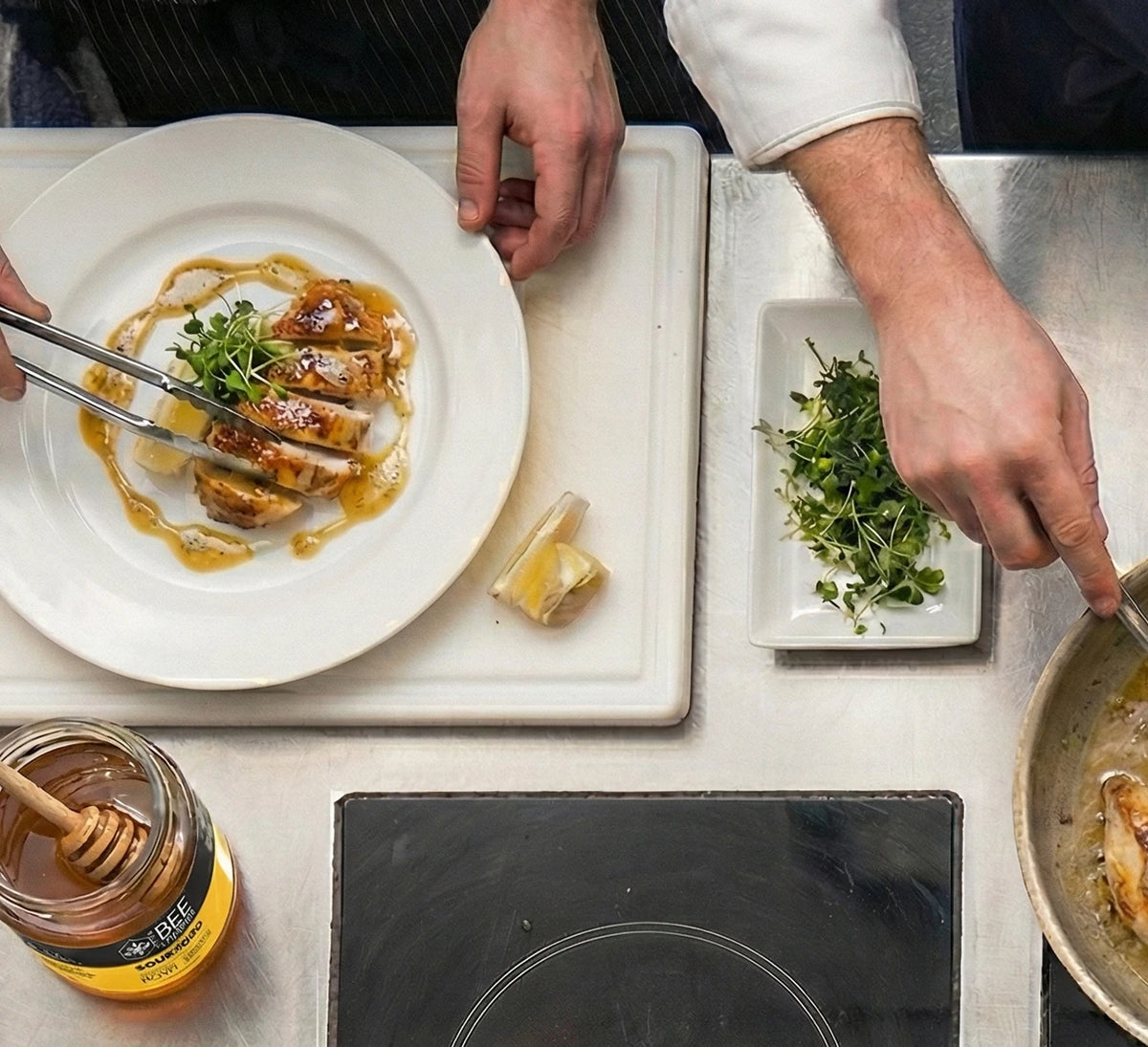 Two chefs plating a dish prepared with The Bee Charmer's Sourwood Honey.