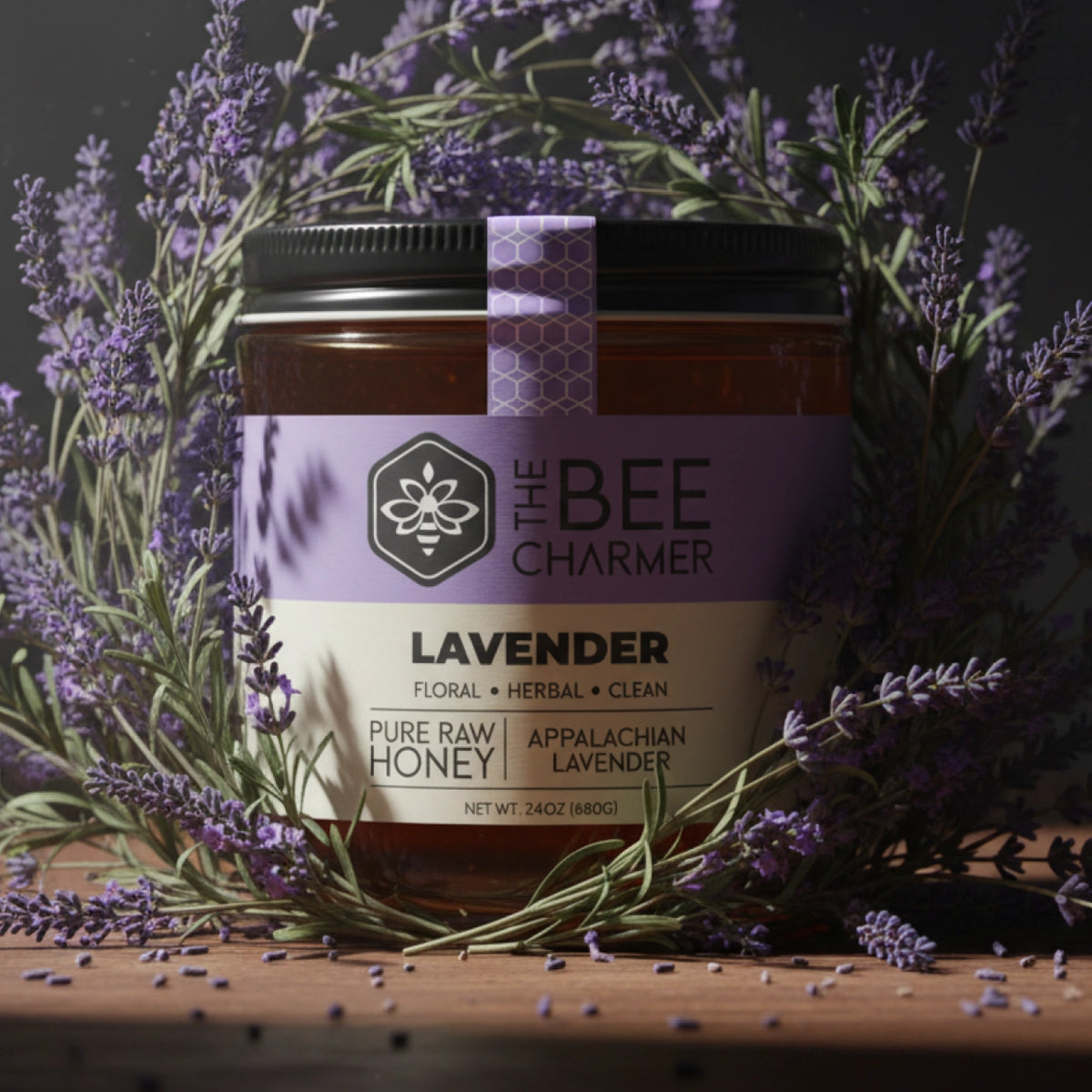 The Bee Charmer 24oz Lavender Honey jar shown along with lavender flower blooms.