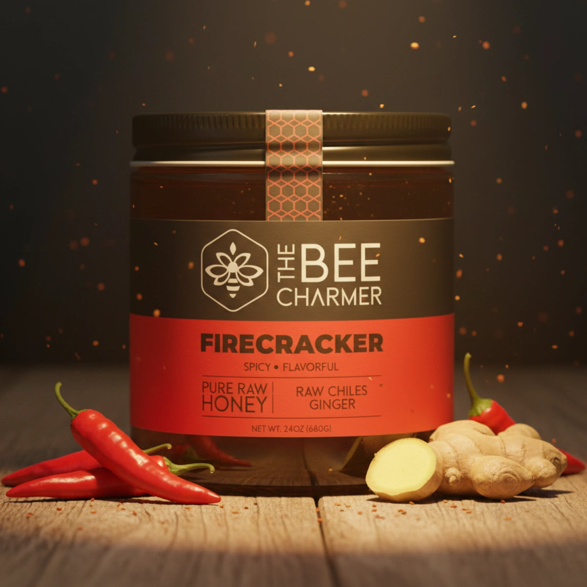 The Bee Charmer 24oz Firecracker Honey jar shown with hot chilies and cut ginger spices.